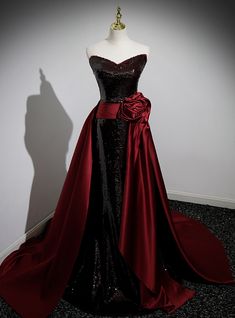 Brought to life with a cascade of sequins, this enchanting black prom dress is the epitome of dark glamour. The gown boasts a flirtatiously straight neckline, transitioning into a sea of shimmering sequins that catch the light with every movement. Embraced at the waist by a wide wine-red satin sash that blooms into an extravagant rosette, the dress spills into a sweeping train that trails with a silent promise of elegance. This garment isn't just a dress; ita centerpiece, a conversation starter, and a treasure that will shine in photos and memories alike. Red Dress Vampire, Black And Red Prom Dress, Vampire Life, Sequin Mermaid Prom Dress, Dark Glamour, Masquerade Outfit, Prom Dress Burgundy, Vampire Dress, Flower Prom Dress