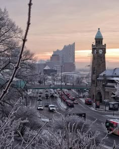 a city street filled with lots of traffic next to tall buildings and trees covered in snow