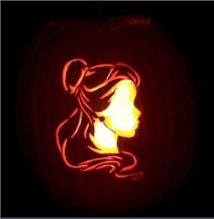 a carved pumpkin with the silhouette of a woman's head on it, in front of a black background