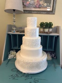 a large white wedding cake sitting on top of a blue table next to a lamp