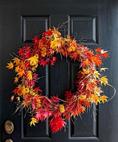 a black door with a wreath made out of autumn leaves on the front and side