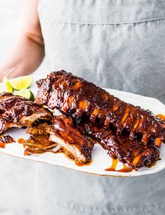 a person holding a plate with ribs covered in barbecue sauce