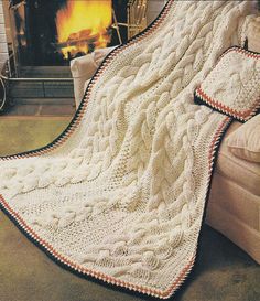 a white blanket sitting on top of a couch next to a fire place