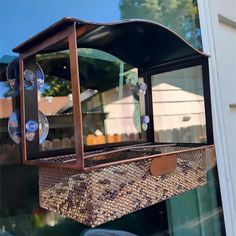 a bird feeder hanging from the side of a building with glass and wood in it