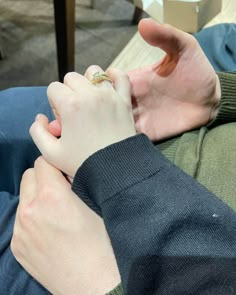 a man is holding the hand of another person who is wearing a ring on their finger