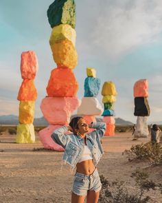 a woman standing in front of a sculpture with her hands on her head and arms behind her head