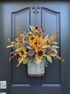 a metal bucket filled with sunflowers and other flowers hanging on a blue door