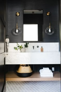 a black and white bathroom with two sinks, mirrors and towels on the counter top