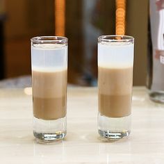 two glasses filled with liquid sitting on top of a table