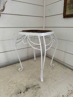 a white metal table sitting on top of a floor next to a deer antler