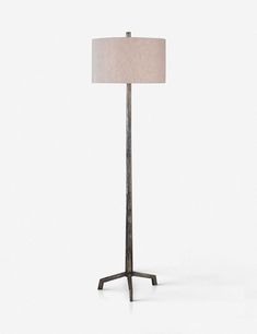 a floor lamp with a beige shade on it's side and a white background