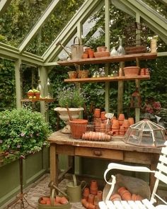 a greenhouse filled with lots of potted plants and pots on top of a wooden table