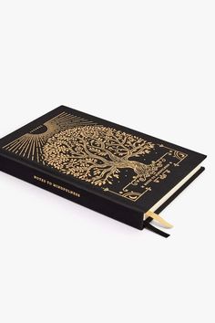 a black and gold book with an intricate design on the cover, sitting on a white surface