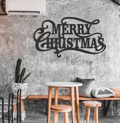 a merry christmas sign on the wall next to two stools and a small table