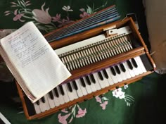 an old musical instrument sitting on top of a green tablecloth with flowers around it