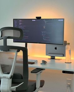 a computer desk with a monitor, keyboard and mouse next to a chair in front of it