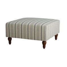 a striped ottoman sitting on top of a white floor next to a wooden leg rest