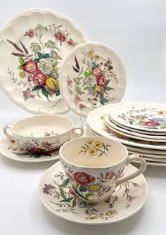 an assortment of porcelain dishes and cups with floral designs on them, all stacked together