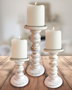 three white candles sitting on top of a wooden table