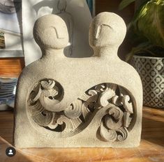 a stone sculpture sitting on top of a wooden table next to a potted plant