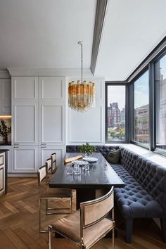 a dining room table with chairs and a bench in front of a window overlooking the city