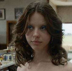 a close up of a woman with no shirt on in a kitchen and looking at the camera