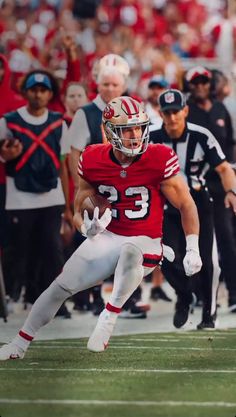 a football player running with the ball in his hand and people watching from behind him