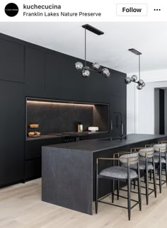 a large kitchen with black cabinets and counter tops, along with bar stools in front of the island