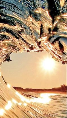 the sun is shining through an ocean wave