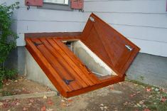 an open wooden box sitting on the side of a house