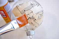 a glass ornament with music notes on it and a paintbrush next to it