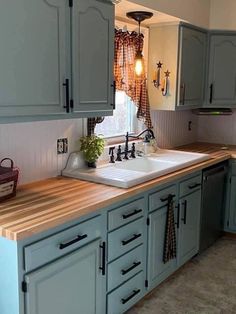 a kitchen with blue cabinets and wooden counter tops, including a white farmhouse style sink