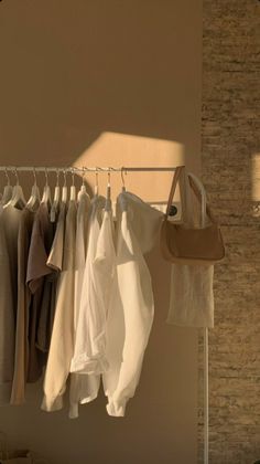 clothes hanging on a rack in front of a brick wall with the sun shining through