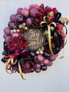 a christmas wreath hanging on the wall with ornaments around it and a joy to the world sign