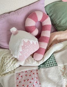 a pink and white stuffed animal laying on top of a bed next to pillows, blankets and pillow covers