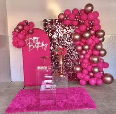 a pink and gold birthday party with balloons on the wall, cake stand and table