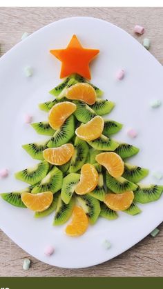 a white plate topped with sliced kiwis and orange slices next to a star