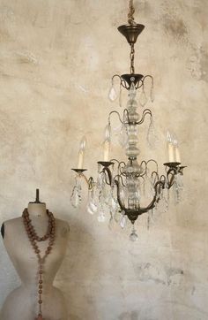 an old fashion chandelier and necklace on display in front of a stucco wall