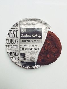 a piece of newspaper with a chocolate cookie on the plate next to it that has been cut in half