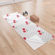 a white table runner with red apples on it next to a block of wood flooring