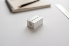 a white object sitting on top of a table next to a pen