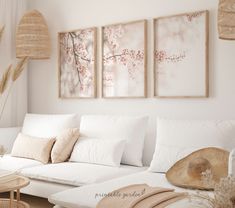 a living room filled with white furniture and paintings on the wall above it's couch