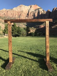 a wooden arch in the middle of a grassy field