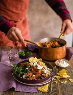 a person in an orange apron is preparing food on a table with tortilla chips and salsa