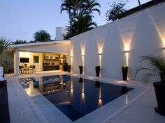 an outdoor swimming pool with lights on the walls and furniture in the back yard area