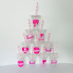 a stack of plastic cups with pink and white straws in them on a table