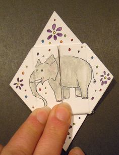 a hand holding up a piece of paper with an elephant drawn on it