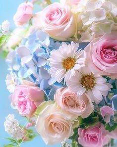 a vase filled with lots of pink and white flowers on top of a blue table