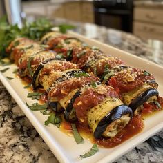 a white plate topped with stuffed shells covered in sauce and garnished with green leaves