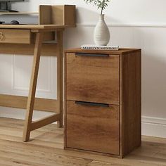 a wooden desk with two drawers and a plant in a white vase on the top